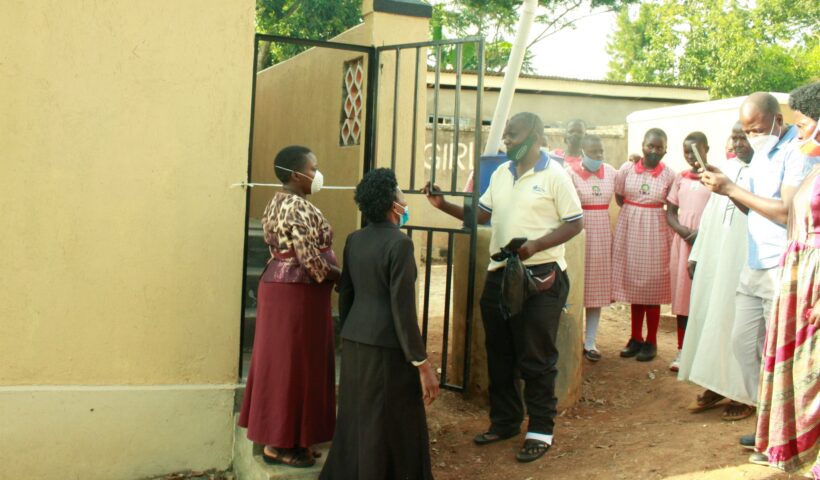 Jimmy Katende handing over the toilet to Nakapinyi Primary School Head Teacher.