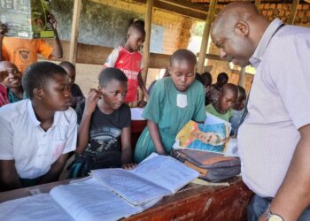 Dr. James Tweheyo, a commissioner at the Office of the President inspecting handwriting skills for learners at Nsonga CoU primary school.