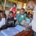 Dr. James Tweheyo, a commissioner at the Office of the President inspecting handwriting skills for learners at Nsonga CoU primary school.