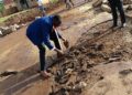 The Lugazi Central Division Chairperson, Lutajan Khemisi showing asphalt surface washed away by running water.