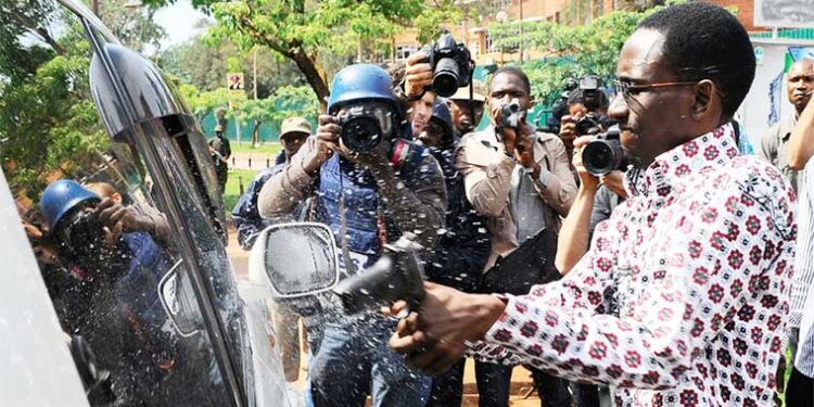 Gilbert-Arinaitwe-smashing-Besigyes-window-with-a-pistol