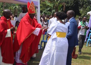 Bishop Rt Rev Lawrence Mukasa receiving gifts from Minister Kyofatogabye Kabuye and his wife after presiding over a mass at Uganda Martyrs Catholic Parish Kiwoko