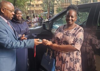 Local Government Minister Raphael Magyezi handing keys to Mukono District CAO, Elizabeth Namanda.