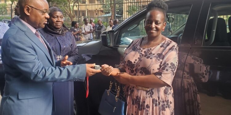 Local Government Minister Raphael Magyezi handing keys to Mukono District CAO, Elizabeth Namanda.