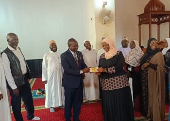Allan Mawanda hands over UGX 5 million to the Chairperson of the Mukono Muslim Women Savings and Cooperative SACCO.