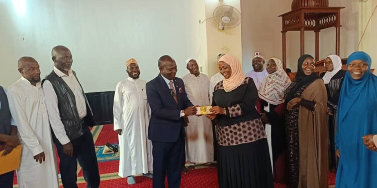 Allan Mawanda hands over UGX 5 million to the Chairperson of the Mukono Muslim Women Savings and Cooperative SACCO.
