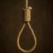 Close-up of a noose made from thick rope, suspended against a dark background.