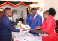 Mukono Returning Officer, Mark Muganzi Mayanja, handing over nomination forms to Johnson Muyanja Ssenyonga.
