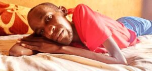 Joseph Sentamu, a patient with MND laying down in his house. Photo by Davis Buyondo