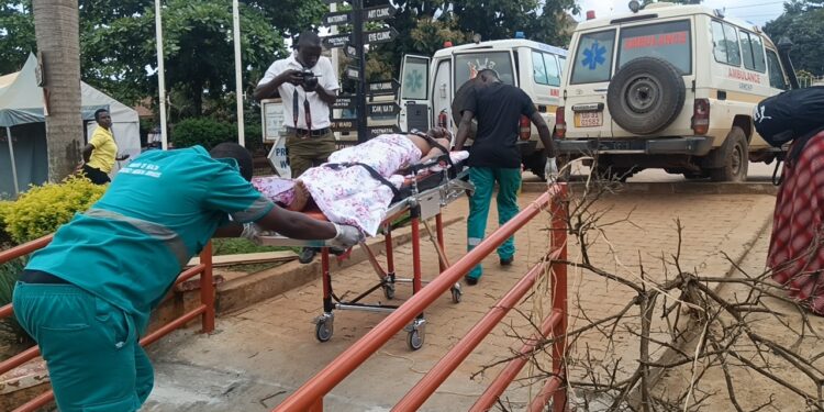 rancis Mpalanyi, Mukono municipal enforcement officer, is transferred to Mulago National Referral Hospital after sustaining serious head injuries during a road reserve kiosk demolition operation in Gunga Village.