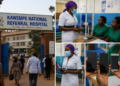 image showing scenes from Kawempe National Referral Hospital, including the hospital entrance with people walking in, nurses interacting with patients inside the wards, and close-up shots of health workers holding mobile phones, illustrating the incident.