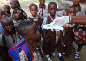 Health workers screen pupils at a school entrance as part of strengthened Ebola prevention measures