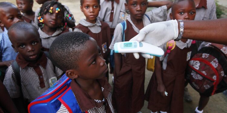 Health workers screen pupils at a school entrance as part of strengthened Ebola prevention measures