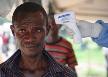 Medical personnel carry out Ebola screening measures at a border point between Uganda and DR Congo.