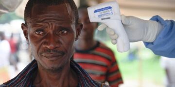 Medical personnel carry out Ebola screening measures at a border point between Uganda and DR Congo.