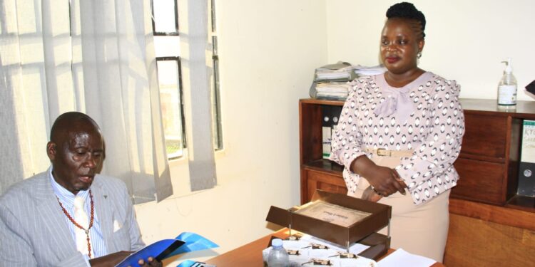 Kaliisizo Town Council Chairperson (Mayor) Richard Sande Ntambaazi handing over the official handover report to the Town Clerk, Resty Nabatanzi, marking the end of his 20-year tenure.