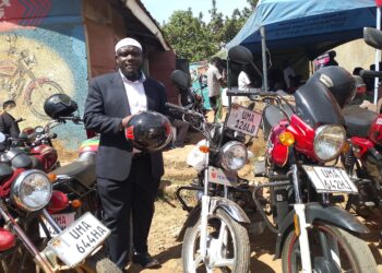 Goma Division Chairperson Hussein Ddumba Kato poses for a photo with one of the newly acquired motorcycles during the handover ceremony at the sacco offices in Mukono Municipality.