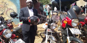Goma Division Chairperson Hussein Ddumba Kato poses for a photo with one of the newly acquired motorcycles during the handover ceremony at the sacco offices in Mukono Municipality.