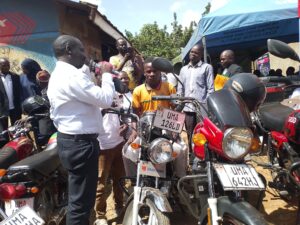 Assistant RDC for Mukono Municipality James Mutyabule hands over one of the motorcycles to beneficiary David Tukei during the distribution ceremony at Goma Division Sacco offices in Mukono Municipality.