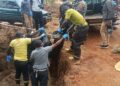 Police Officers carrying the remains of the decomposed body found in the trench at Lweza