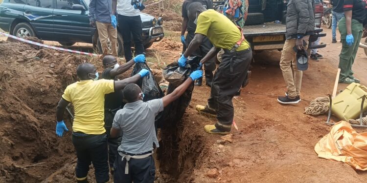 Police Officers carrying the remains of the decomposed body found in the trench at Lweza