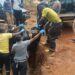 Police Officers carrying the remains of the decomposed body found in the trench at Lweza