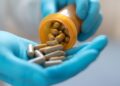 Herbal alternative medicine in capsules in prescription hospital bottle in doctor hand. Organic herb drug for natural treatment
