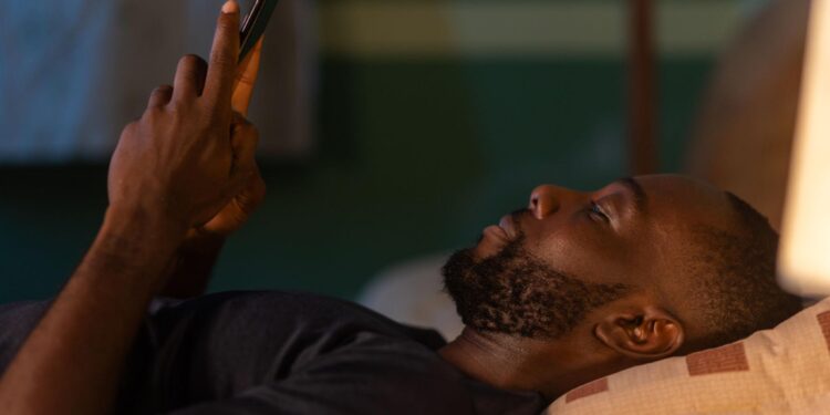 A man uses his smartphone late at night, reflecting how prolonged AI conversations often happen in isolation.