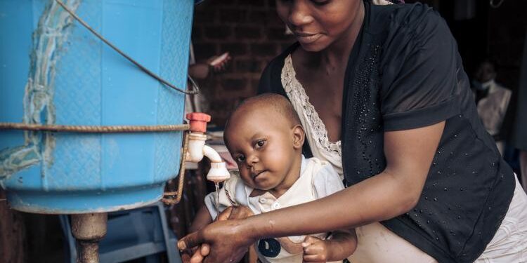 Mother washing baby’s hands with clean water and soap to help prevent foodborne infections and promote good hygiene.