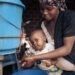 Mother washing baby’s hands with clean water and soap to help prevent foodborne infections and promote good hygiene.