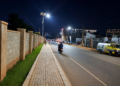 Pedestrians and motorists use a newly reconstructed, solar street lit road and paved walkway in Mukono Municipality at night. The upgraded infrastructure is intended to improve road safety, mobility, and accessibility for both motorists and pedestrians.
