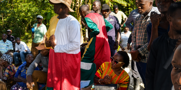 Nalongo Maggie Kaweesi sits beside 'Kabaka' Nakibinge as he addresses residents during a meeting at a contested piece of land.