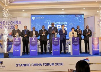 Minister David Bahati (3rd left) posing for a photo with the Stanbic Uganda team led by the Bank's Chief Executive Mumba Kalifungwa(centre) after the launch