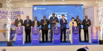 Minister David Bahati (3rd left) posing for a photo with the Stanbic Uganda team led by the Bank's Chief Executive Mumba Kalifungwa(centre) after the launch