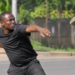 Illustrative photo: A man throws a concrete paver in a simulated attack. The image is used for illustration and does not depict the actual incident involving Minister Justine Nameere’s driver.