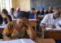 Adult learners attend a lesson in a modest classroom. Thirteen learners in Kawempe, Kampala, reportedly missed the 2026 UCE examinations after discovering they had not been registered. The image is illustrative.