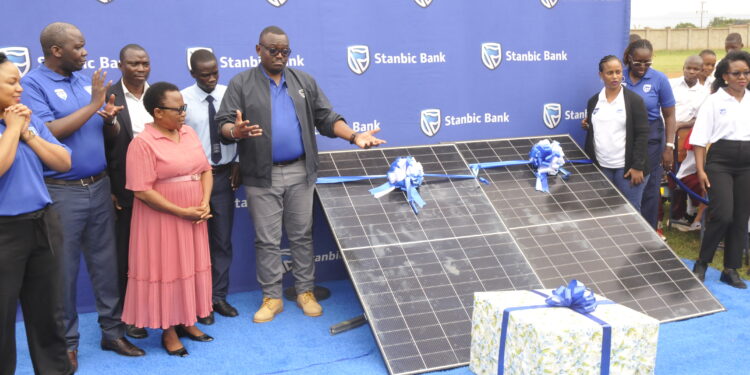 Stanbic's Executive Head of Business and Commercial Banking, Tunde Thorpe, handing over a gift to the acting District Education Officer, Joy Wamalugu
